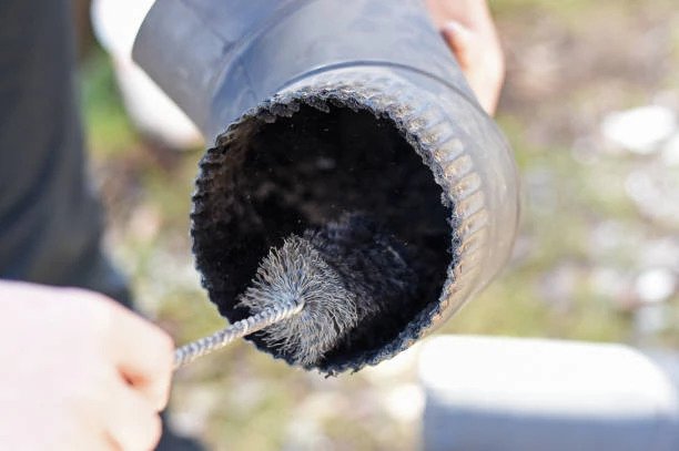 man scrubbing out small pipe with brush